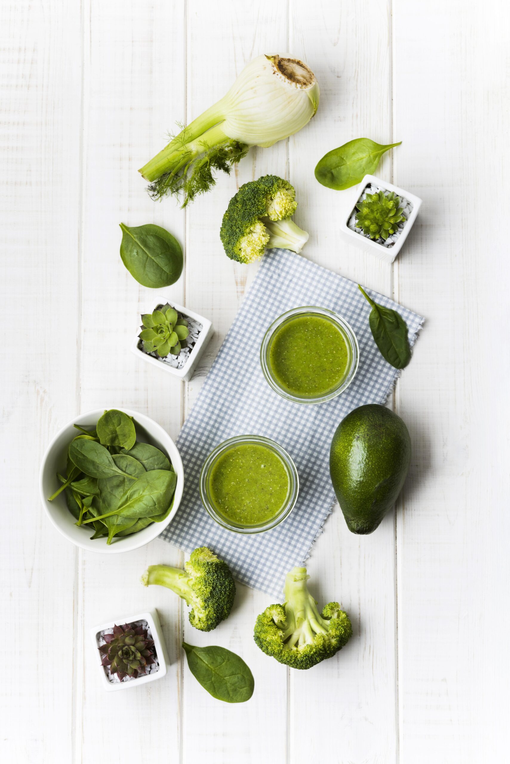 Fresh green vegetables and fruits laid out on a clean countertop.